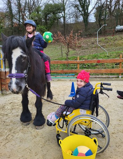 Zwei lächelnde Mädchen interagieren auf einem Reitplatz